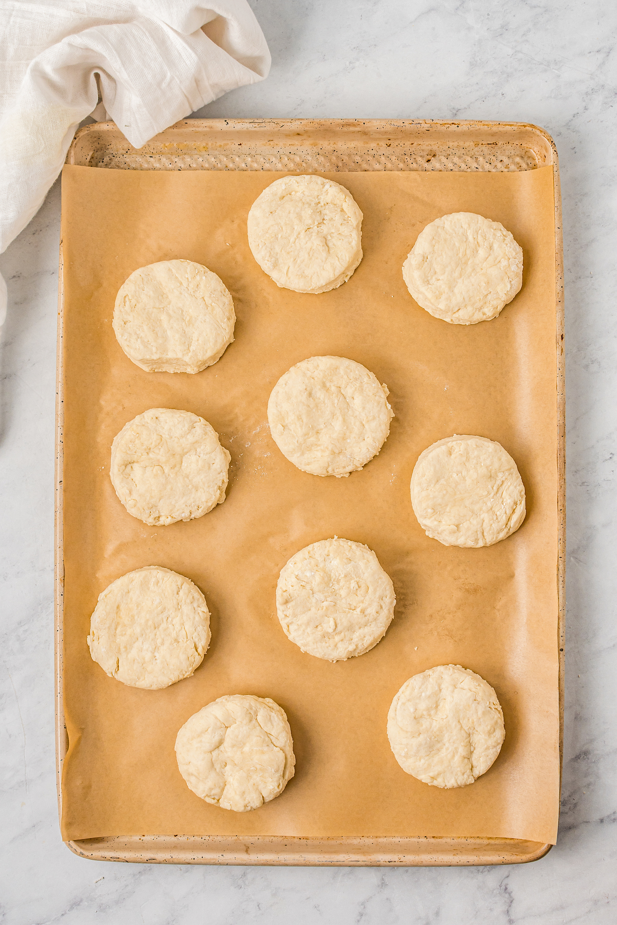 Unbaked biscuits on a parchment-lined baking sheet.