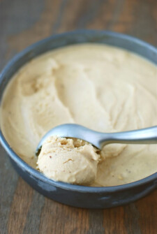 Brown butter ice cream in a pan with a ice cream scooper getting a scoop of ice cream.