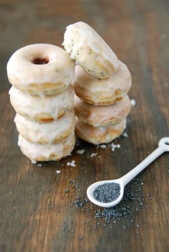 Two stacks of glazed lemon poppy seed donuts.