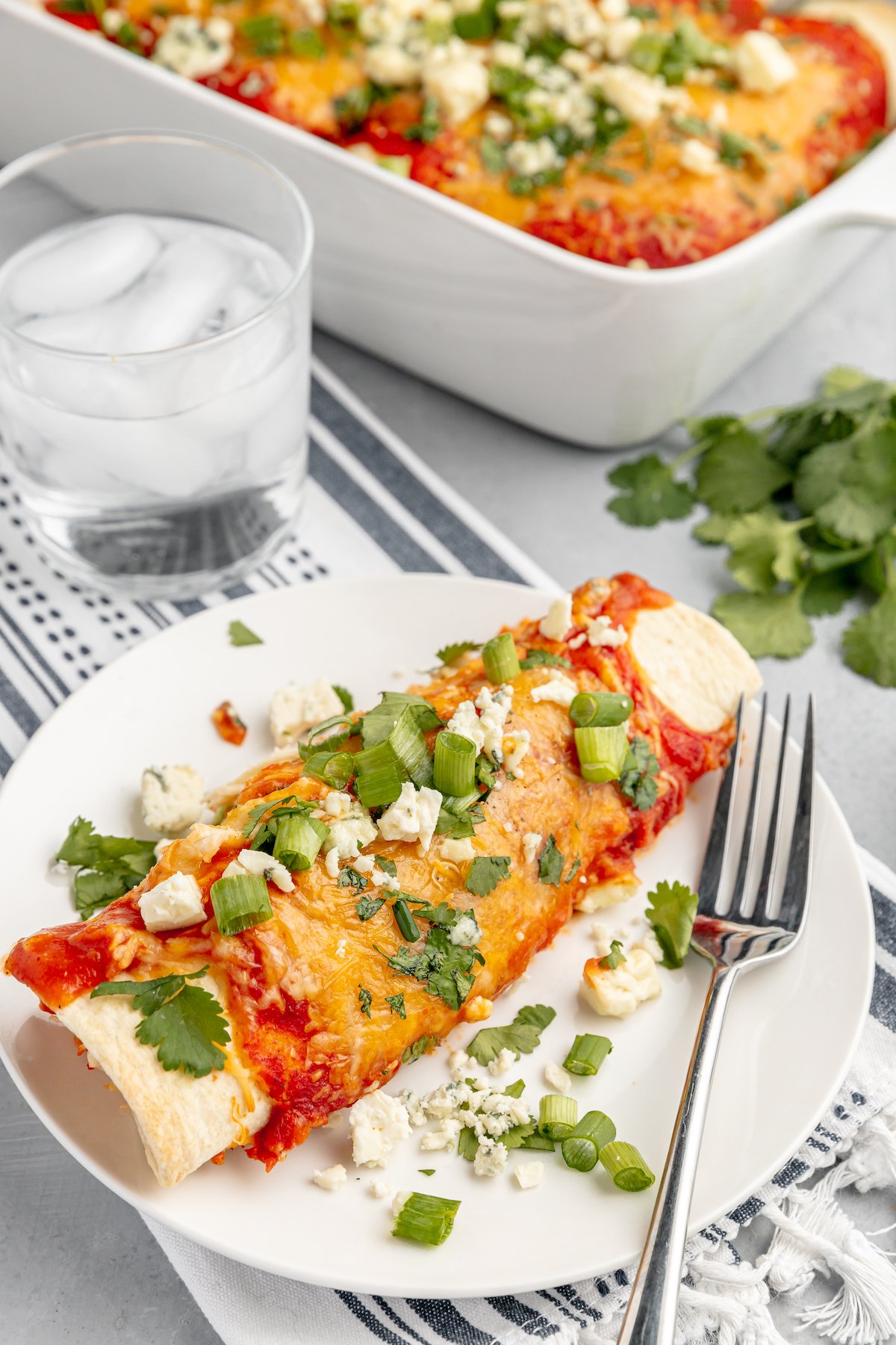 A buffalo chicken enchilada on a small white plate with a fork.