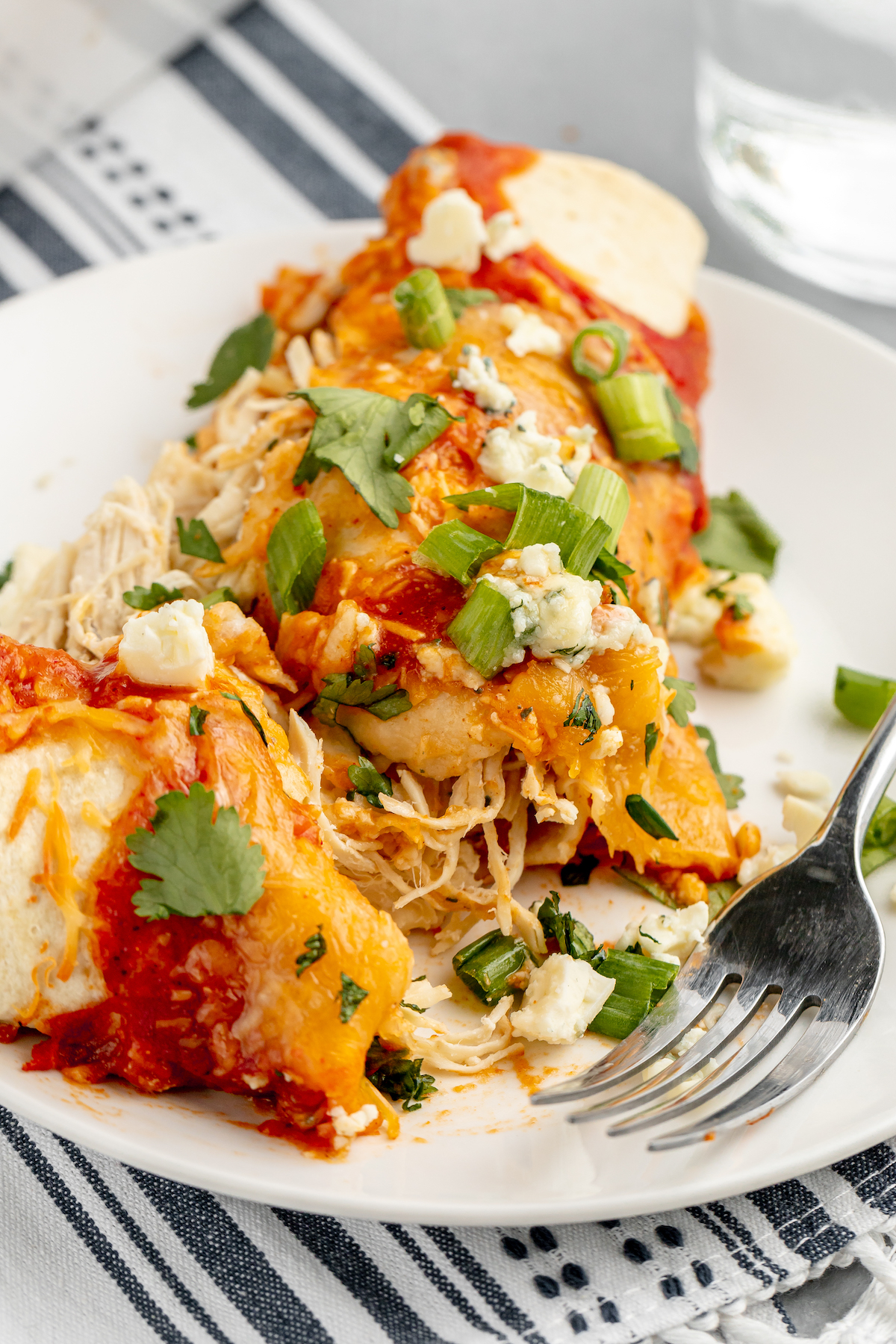 Close-up shot of an enchilada that has been cut in half on a small serving plate, to show the filling.