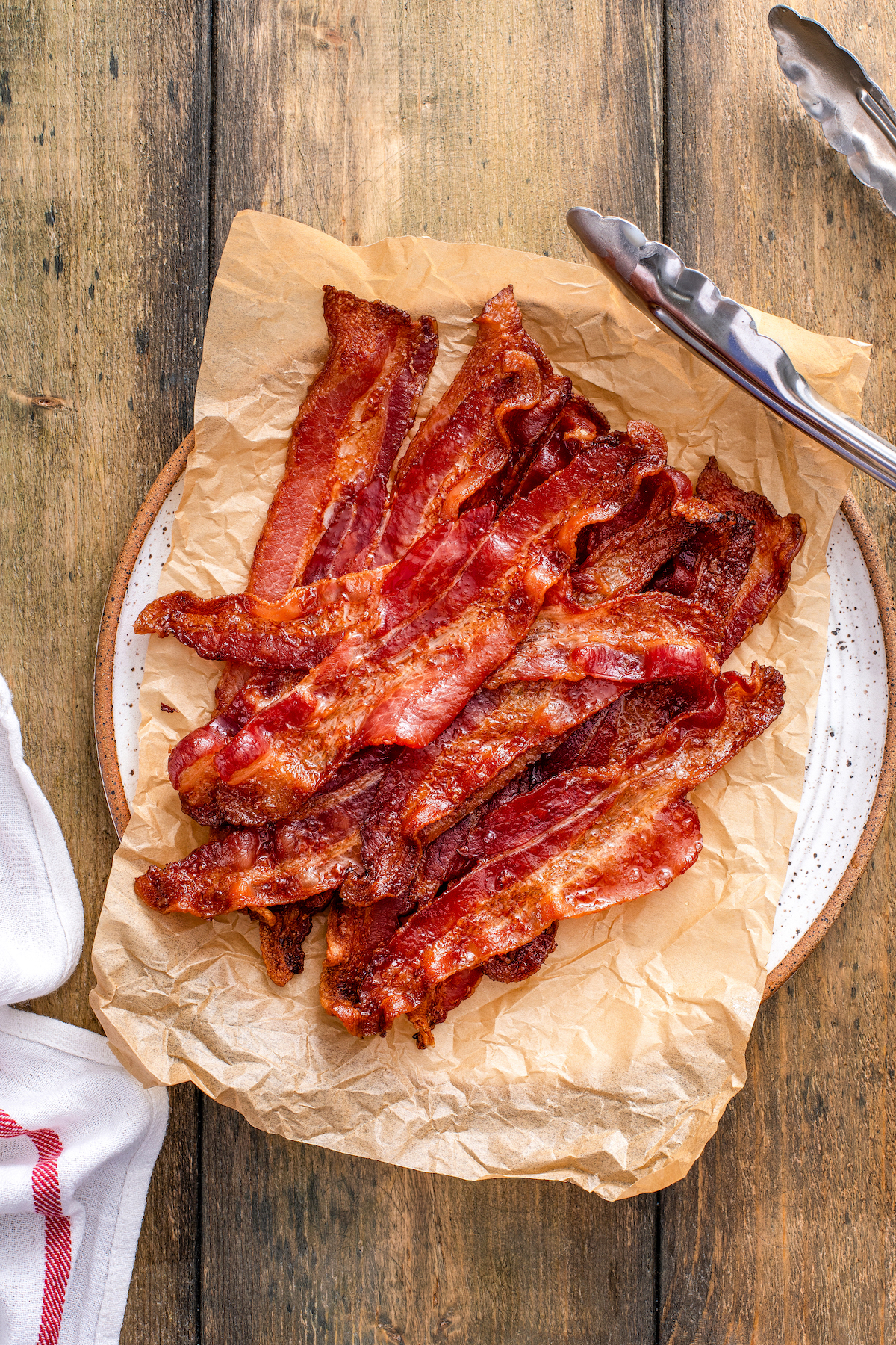 Crispy, smokey oven bacon on a plate lined with parchment paper. 