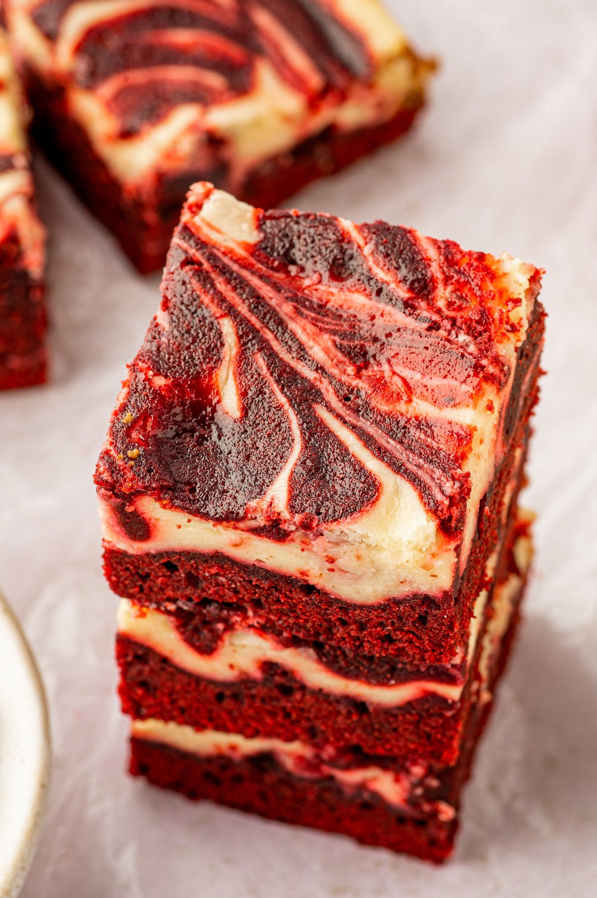 A stack of three rich, moist and fudgy red velvet cheesecake brownies. 