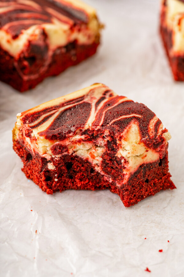 Red velvet brownie with swirls of sweet cream cheese with a bite taken out of it to show the moist inside. 