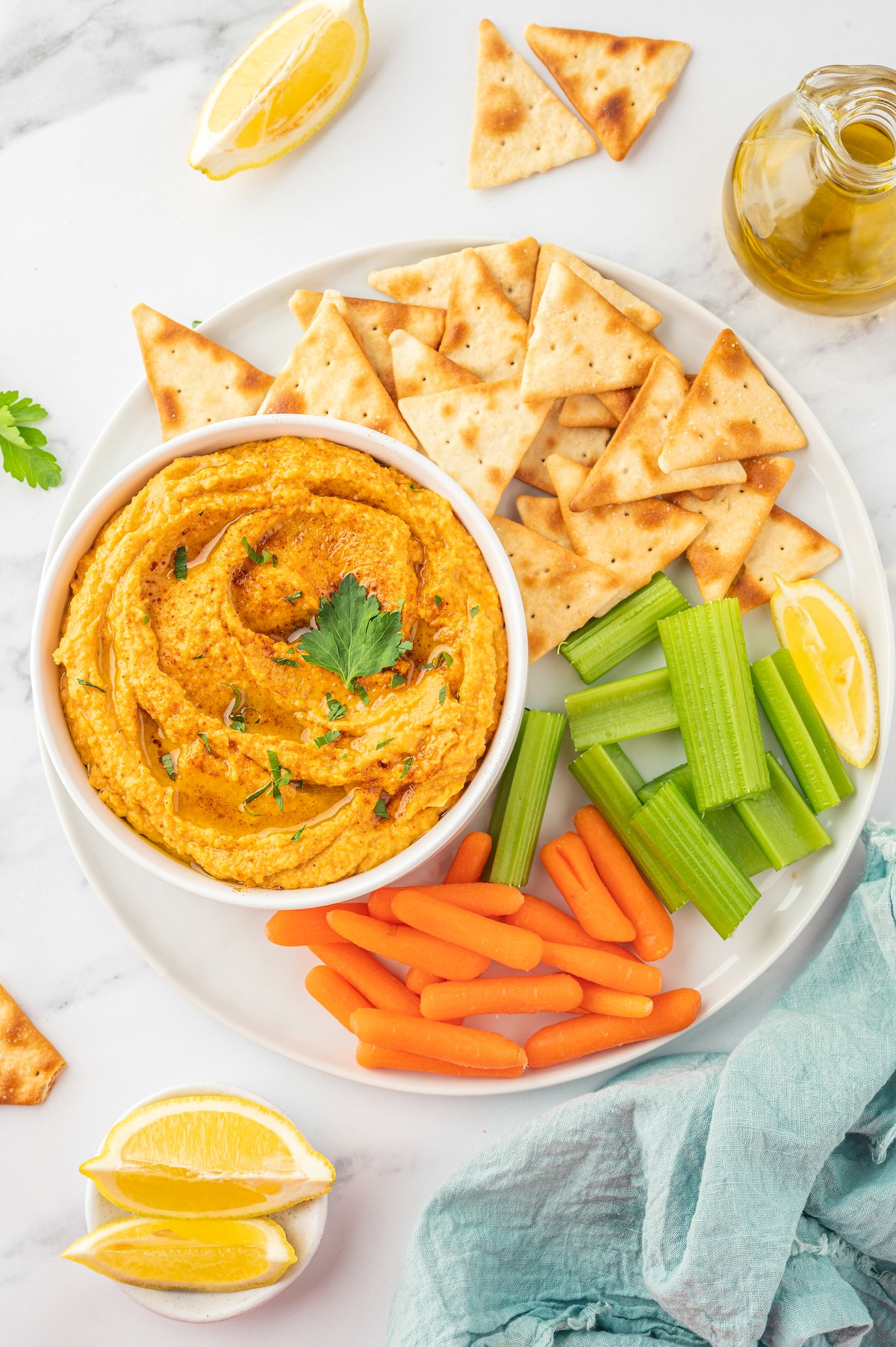 Bowl of sweet potato hummus with pita chips, celery sticks, and carrot sticks on the side. 
