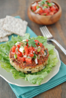 Tuna cake on a piece of lettuce on a plate with salsa on top.