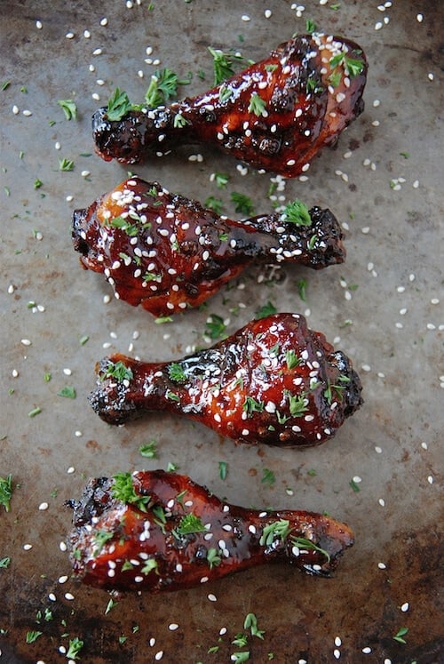 Tray of garnished, baked chicken drumsticks.