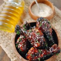 Drumsticks covered in sauce and sesame seeds.