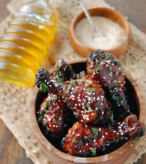 Drumsticks covered in sauce and sesame seeds.