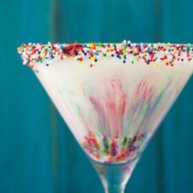 Up close image of cake batter martini with rainbow sprinkles inside and on rim.