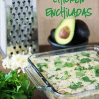 Casserole dish of Spicy Avocado Chicken Enchiladas with a cheese grater and avocados in the background
