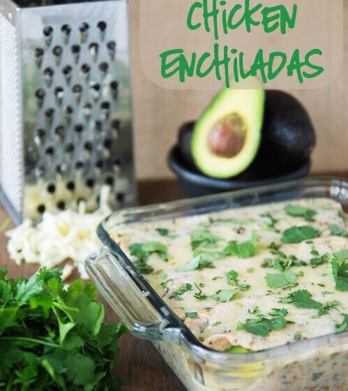 Casserole dish of Spicy Avocado Chicken Enchiladas with a cheese grater and avocados in the background