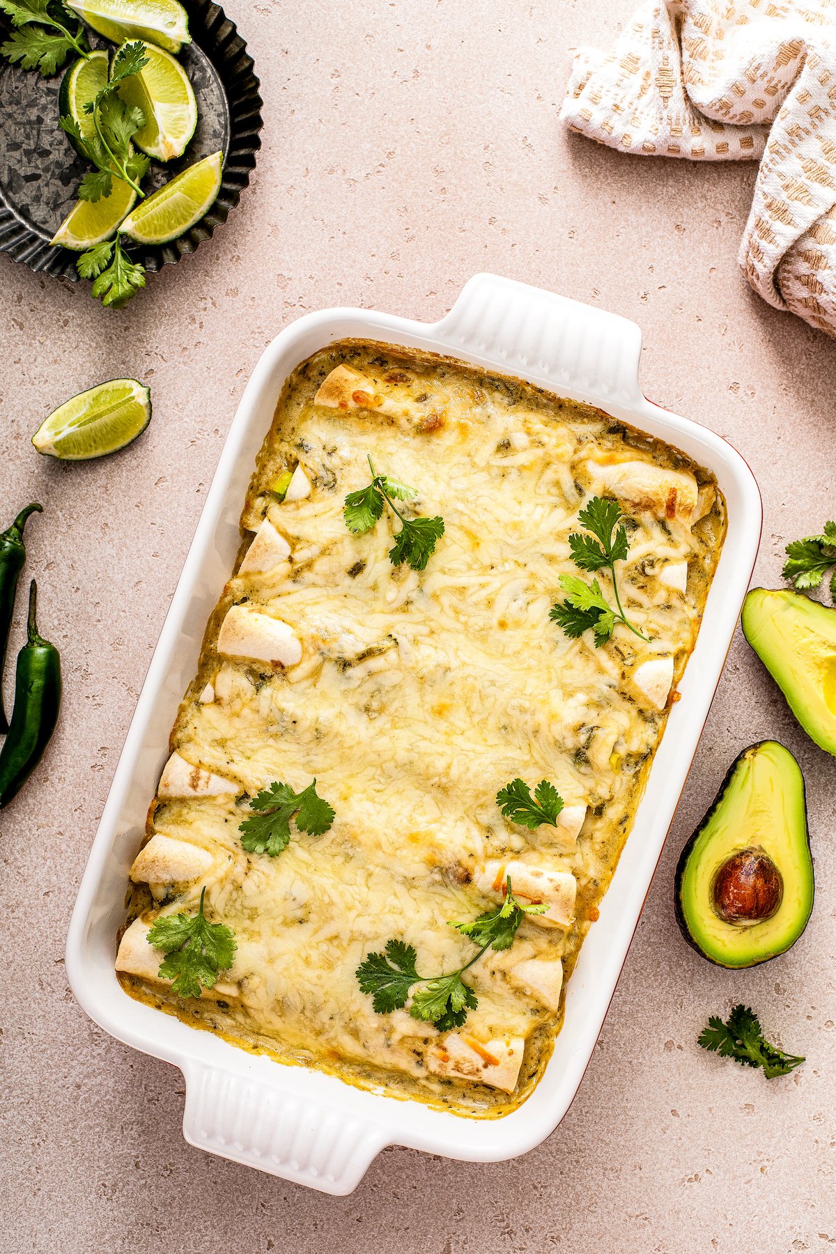 Freshly baked white chicken enchiladas in the baking dish with melty cheese and cilantro on top.