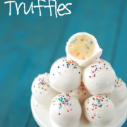 Cake batter truffles with melted almond bark in a bowl.
