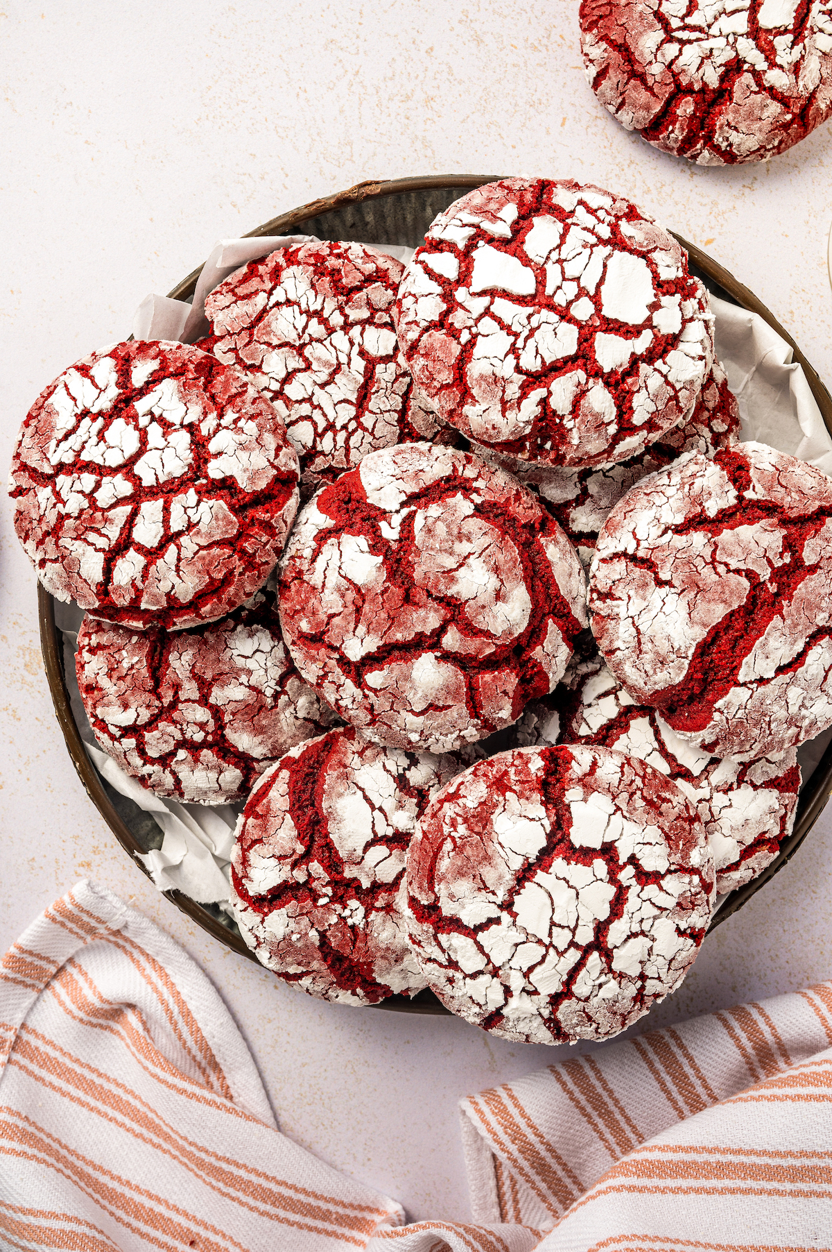 Overhead shot of a platter of red velvet crinkle cookies with a red and white cloth napkin.