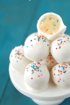 Up close image of cake batter truffles on top of each other on a cake plate.