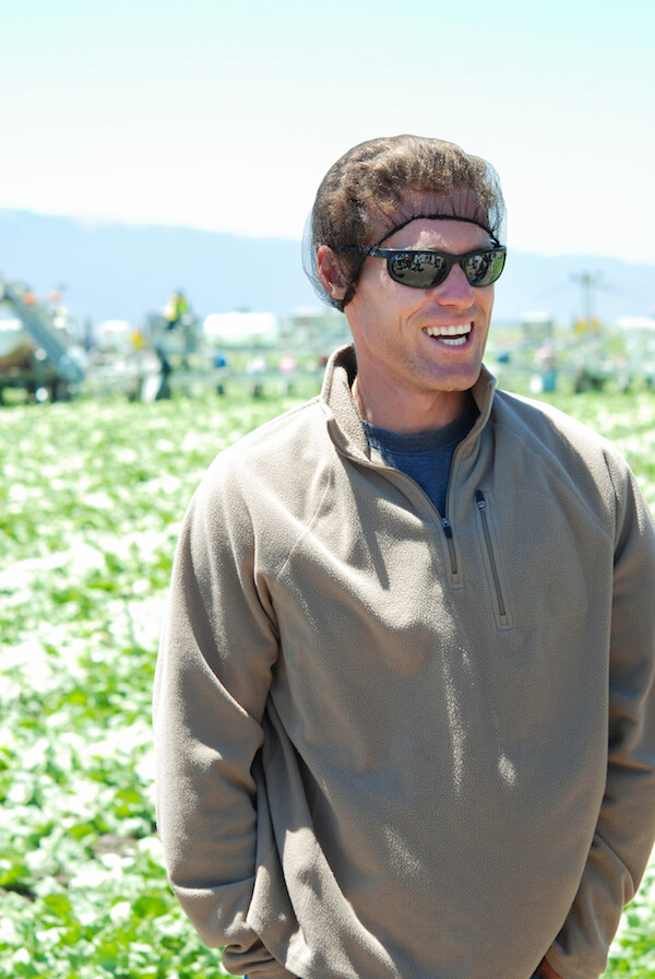 A man with a hair net and sunglasses in a lettuce field