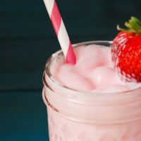 Strawberry Milk with a pink and white straw - topped with a strawberry
