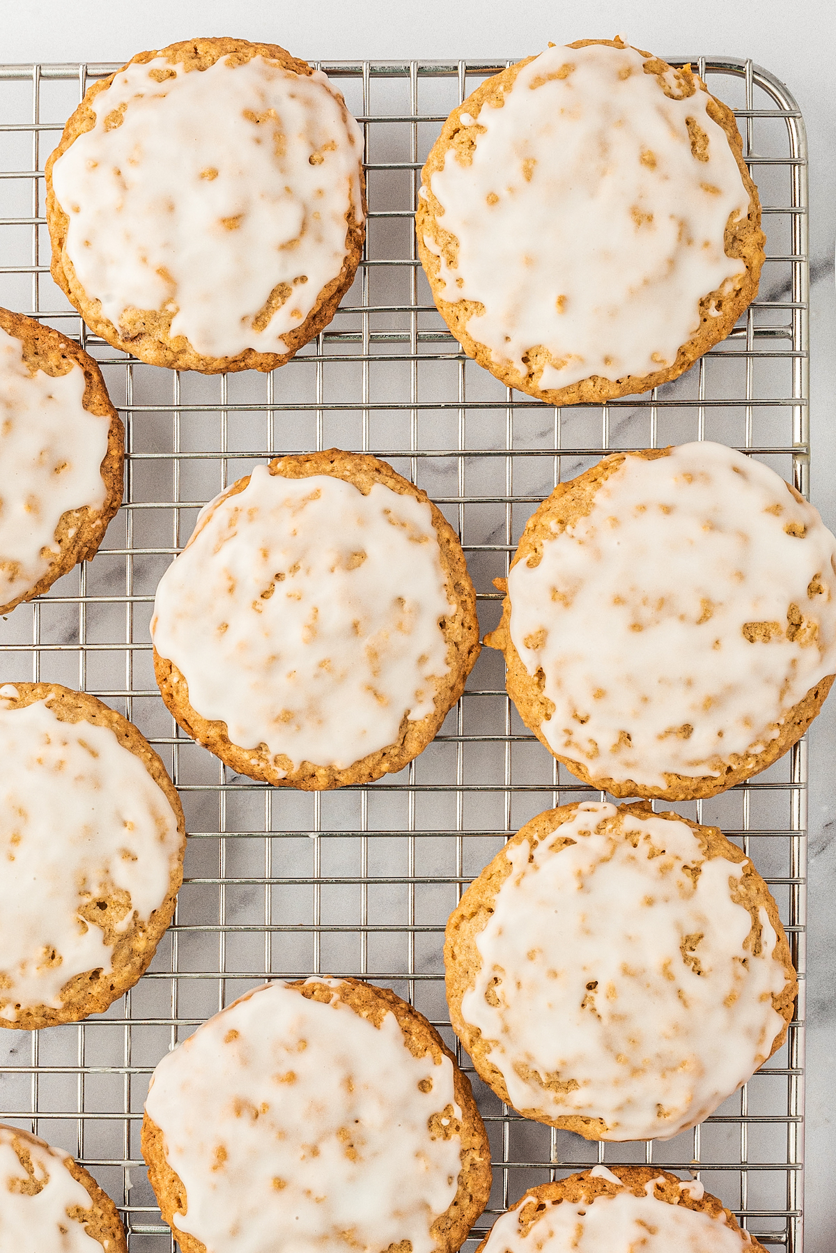 Close-up shot of old fashioned oatmeal cookies, iced and lined up on a wire rack.