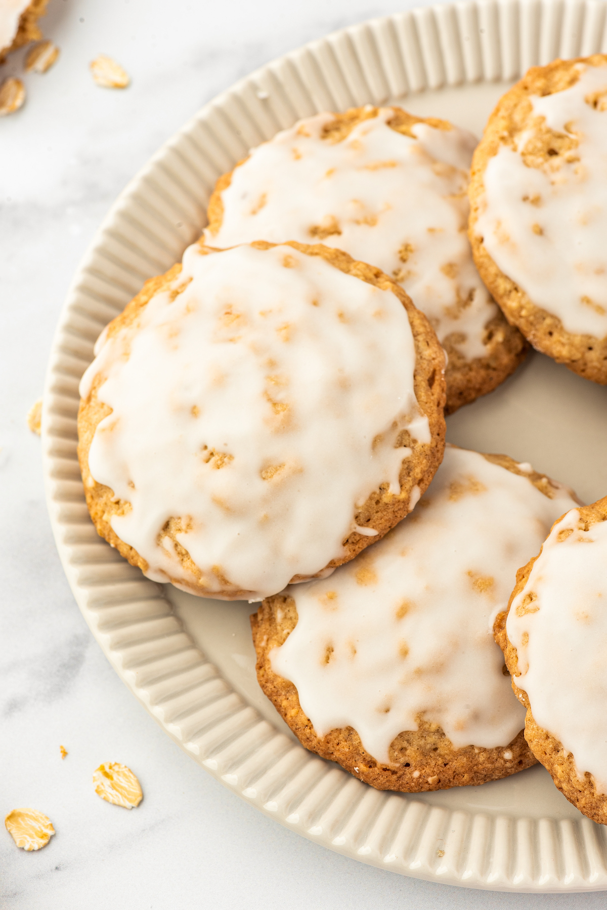 Close-up shot of iced oatmeal cookies arranged in an overlapping circle on a plate.