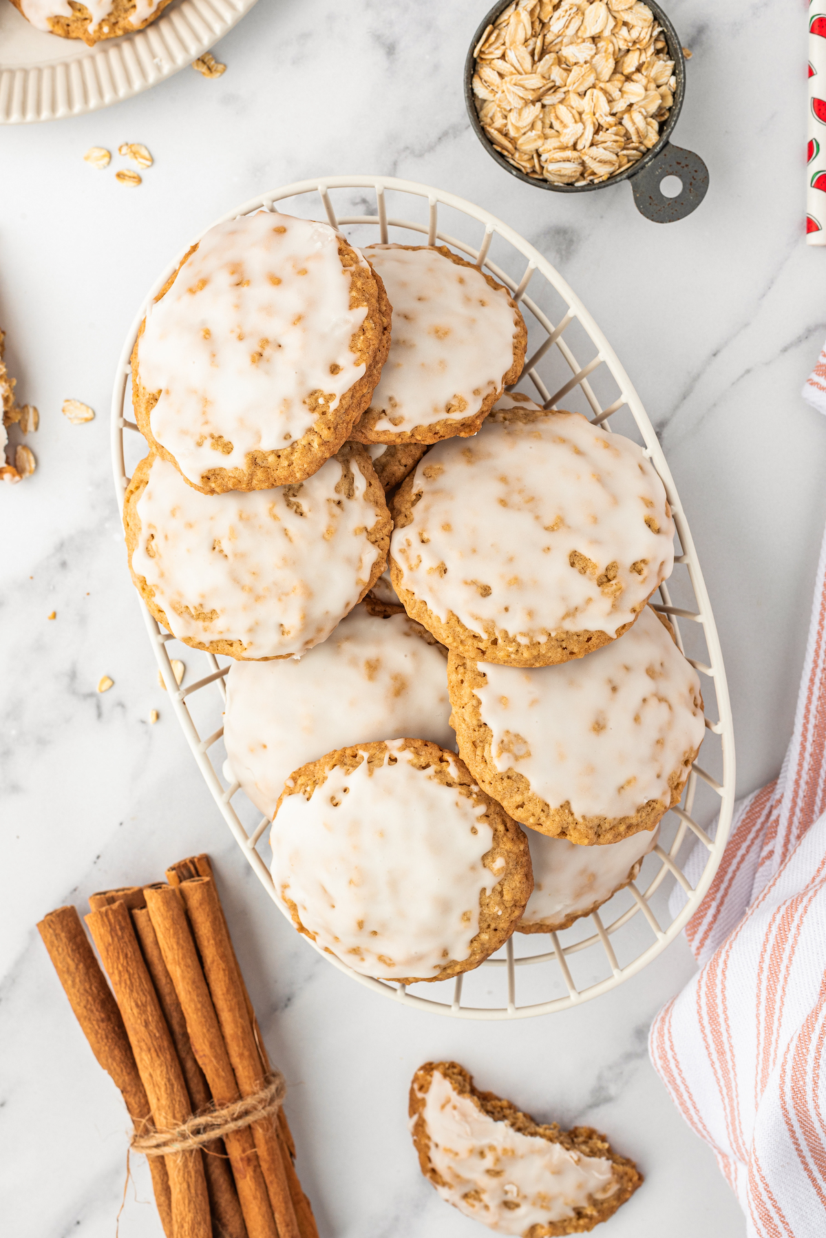 A basket of old fashioned oatmeal cookies, next to a bundle of cinnamon sticks and a striped cloth napkin.