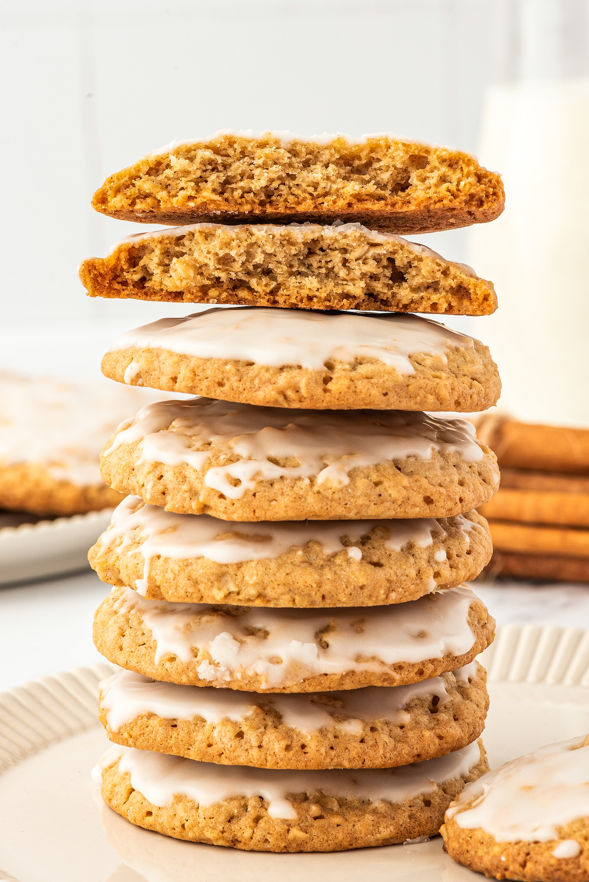 Six oatmeal cookies stacked on top of each other. A seventh cookie has been broken in half to show texture, with the halves balanced on top of the stack.