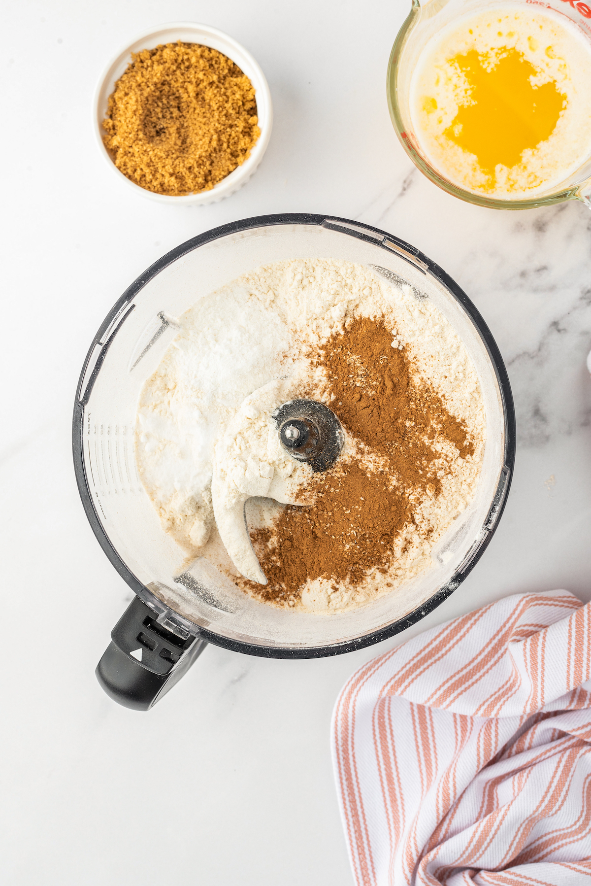 Overhead shot of a food processor with flour, ground oats, and spices inside.