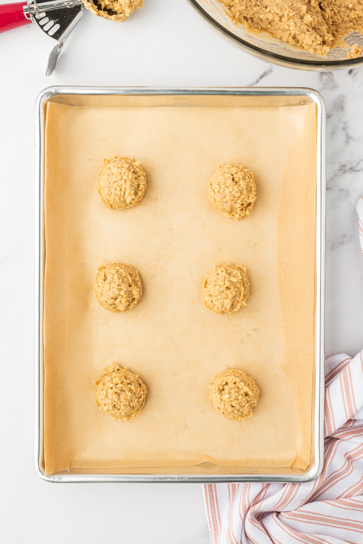 Unbaked drop cookies on a baking sheet.