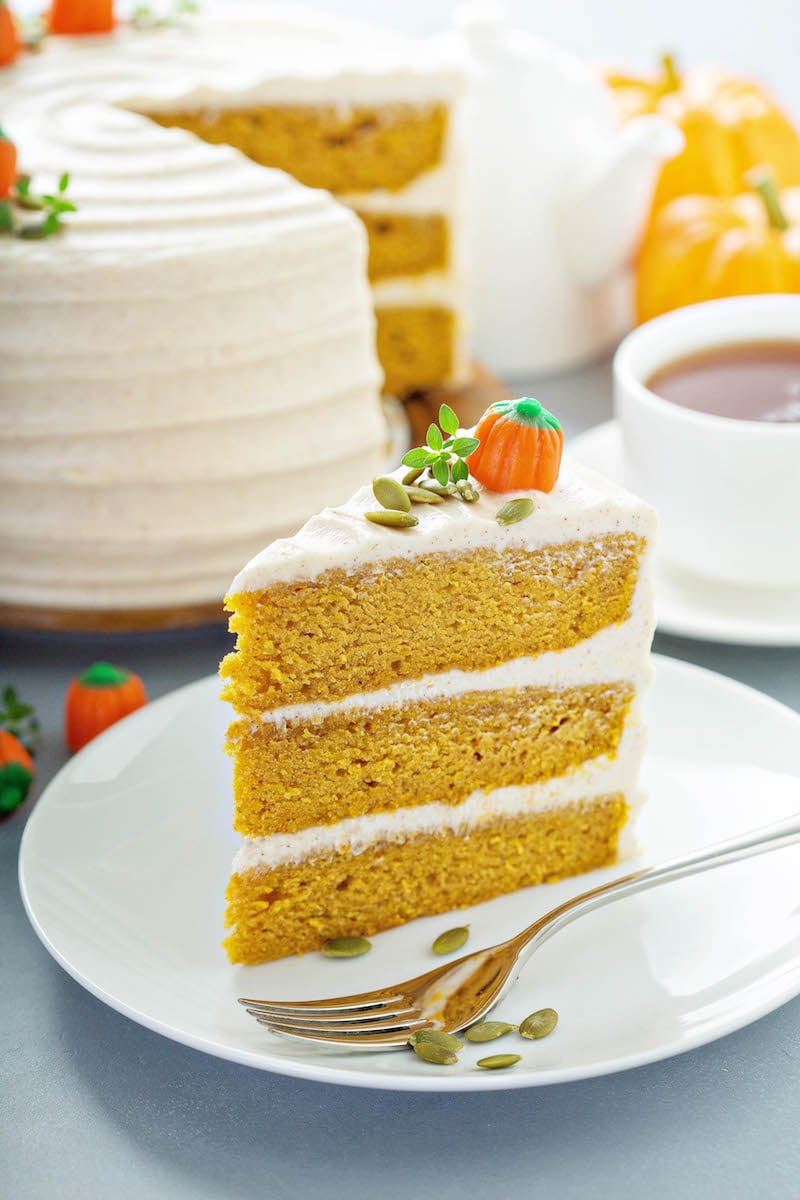 Pumpkin Cake slice with three layers and cream cheese icing on a plate.