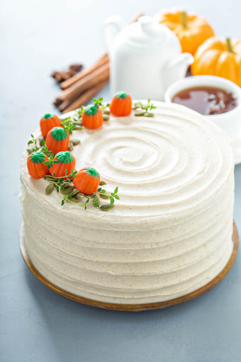 Pumpkin Cake with cream cheese icing with pumpkin candies on top with thyme like a vine.