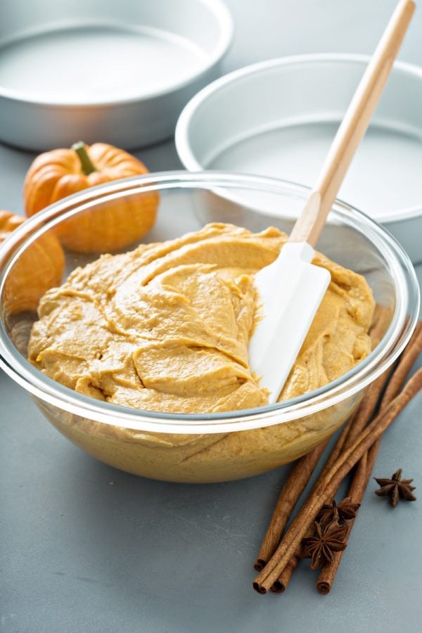 Pumpkin cake batter in a bowl with a spatula. 