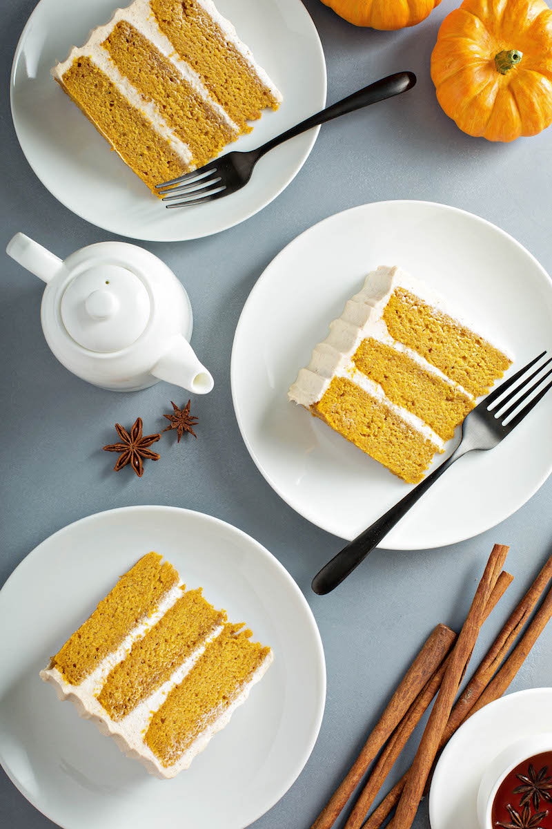 Three slices of pumpkin cake on white plates.