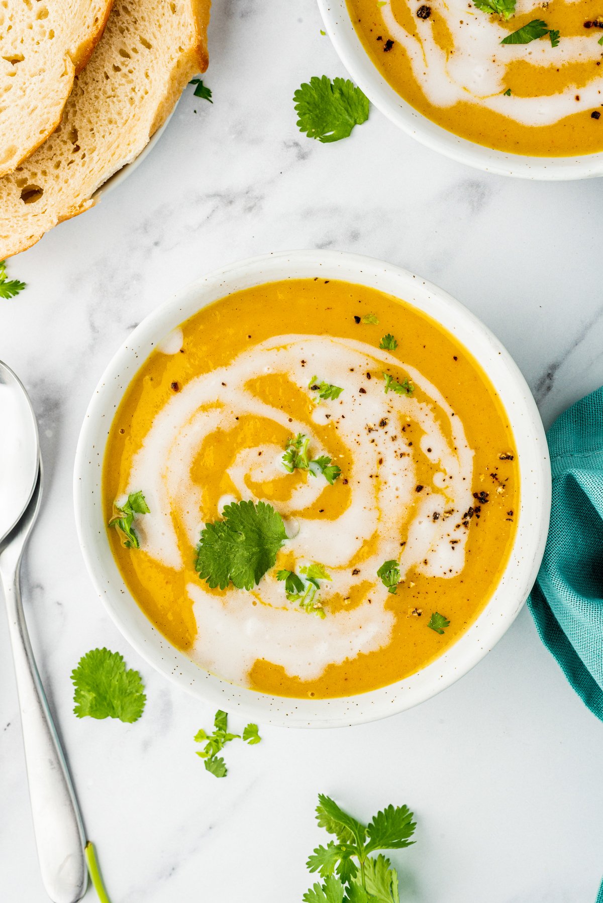 a bowl of butternut squash soup with a cream swirl and herb garnish