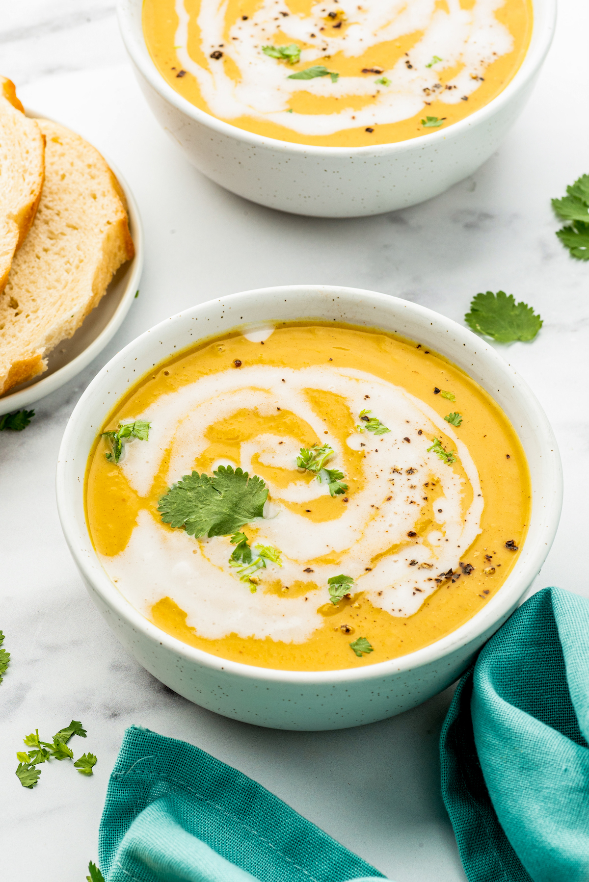a bowl of butternut squash soup with a cream swirl and herb garnish