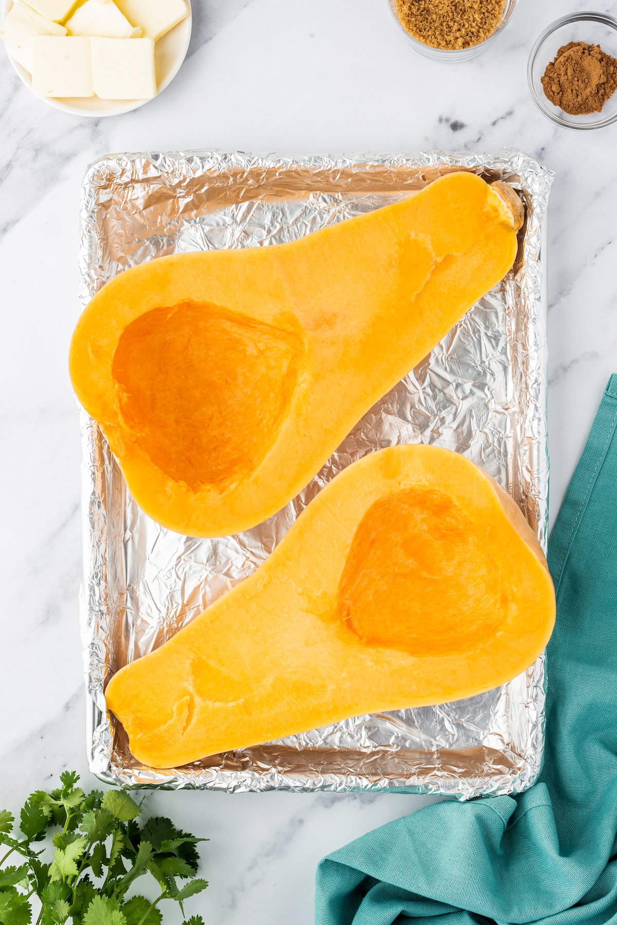 two butternut squash halves, seeded, and on a roasting pan