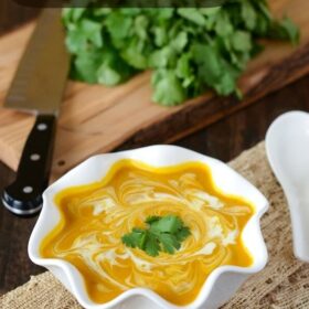 Butternut Squash Coconut Curry Soup in a white bowl topped with coconut cream