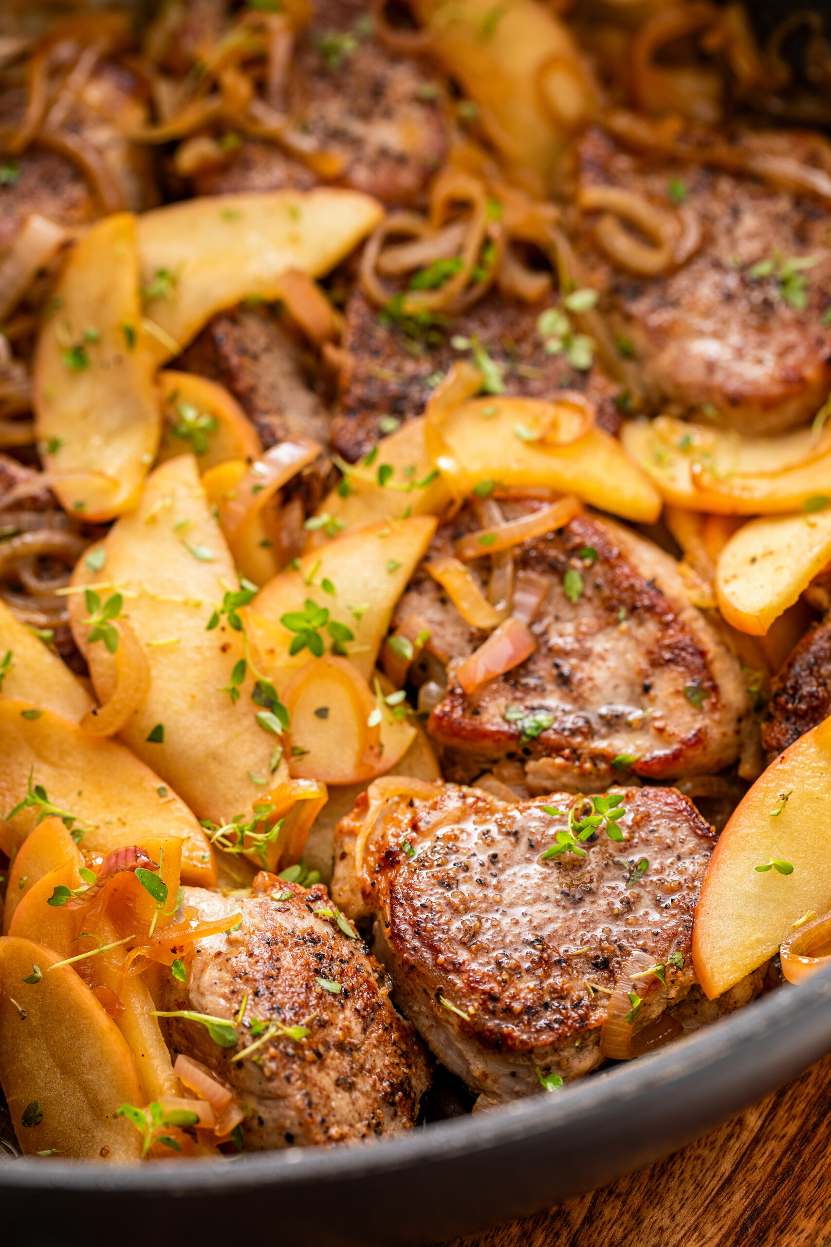 Apple pork loin is garnished with fresh herbs in a shallow bowl. 