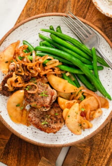 Pork tenderloin with apples served with green beans on the side.