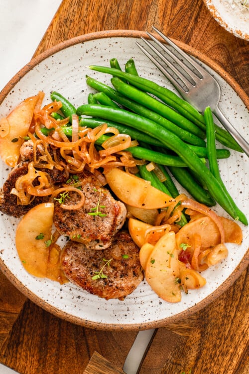 Pork tenderloin with apples served with green beans on the side.