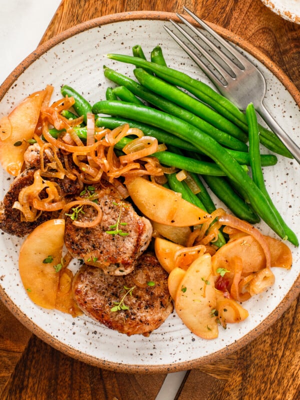 Pork tenderloin with apples served with green beans on the side.