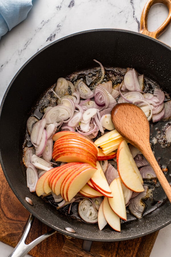 Apples and shallots are cooking in a skillet. 