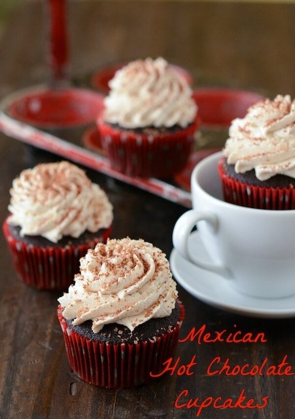 Four Mexican Hot Chocolate Cupcakes on a Wooden Table with a Tea Cup, Saucer and Cupcake Tin