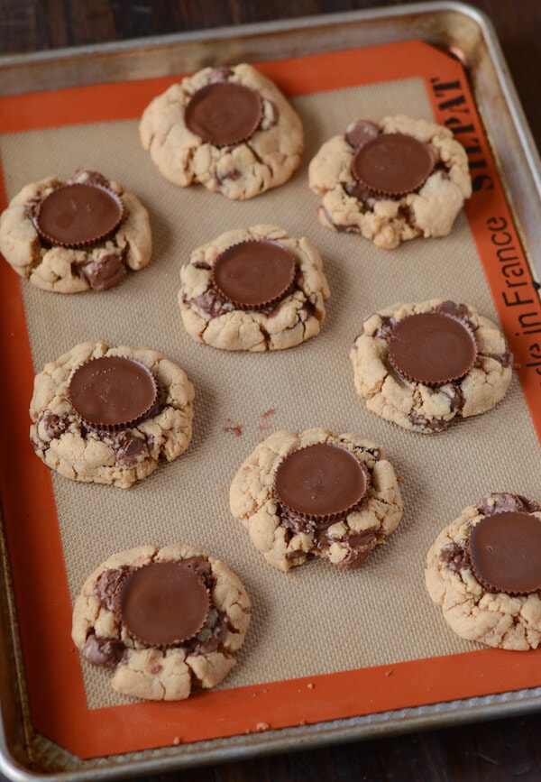 Peanut Butter Cookies topped with Reese's Cups sit on a baking sheet