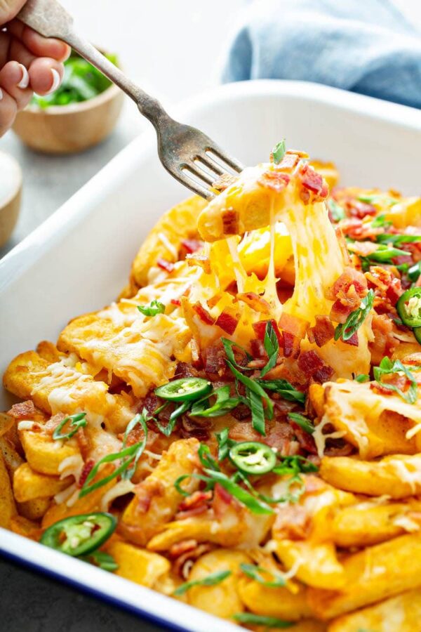 Cheese Fries being pulled out of the pan with a fork. 