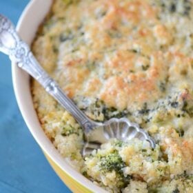 Cheesy Broccoli Quinoa Casserole in a yellow casserole dish with a silver serving spoon