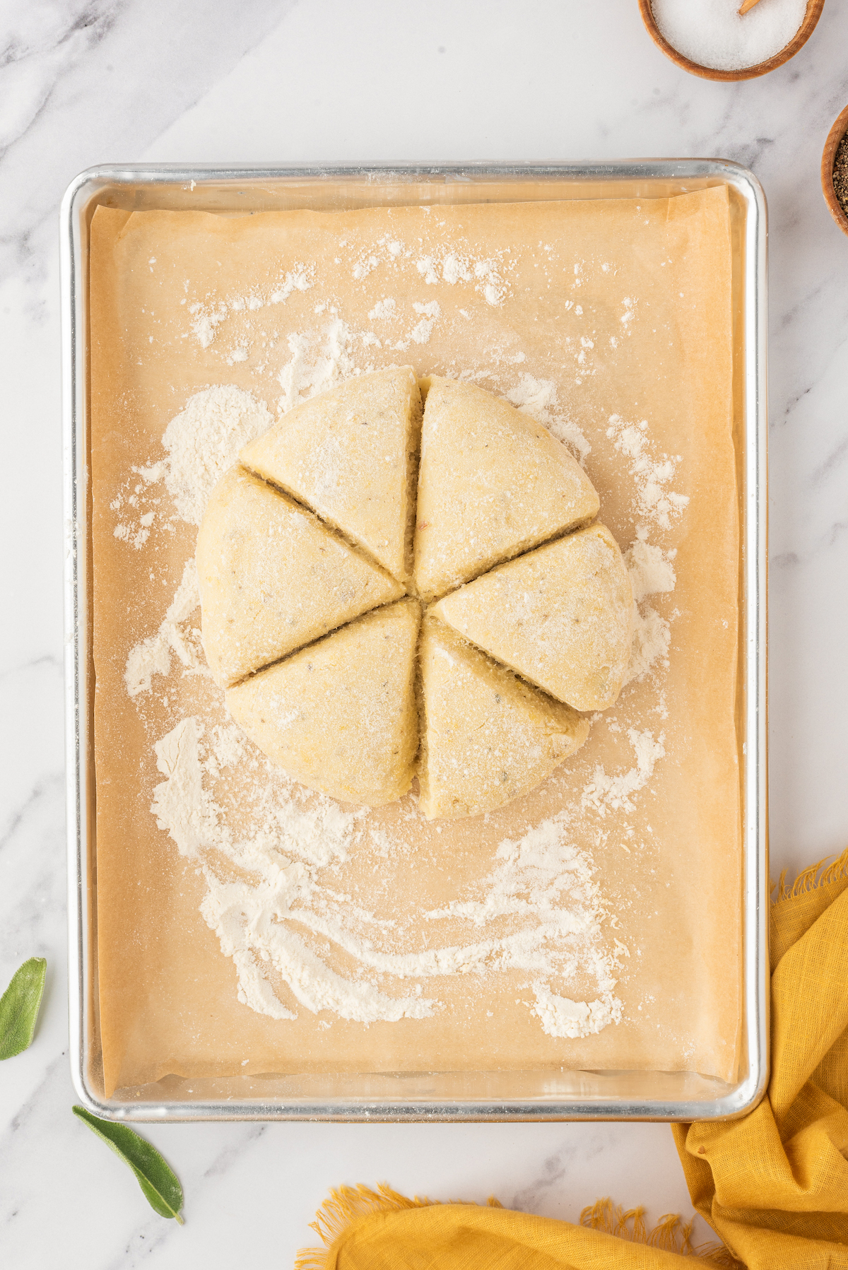 A circle dough on a floured baking tray, divided into six pieces.