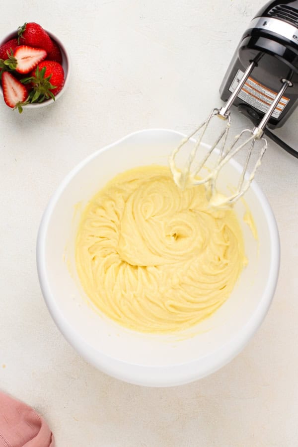 Butter is creamed in a large white mixing bowl.