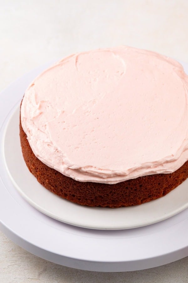 A single strawberry cake layer has been frosted with strawberry buttercream.