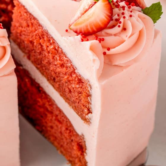 A moist homemade cake is flavored with fresh strawberry puree and topped with pink frosting.