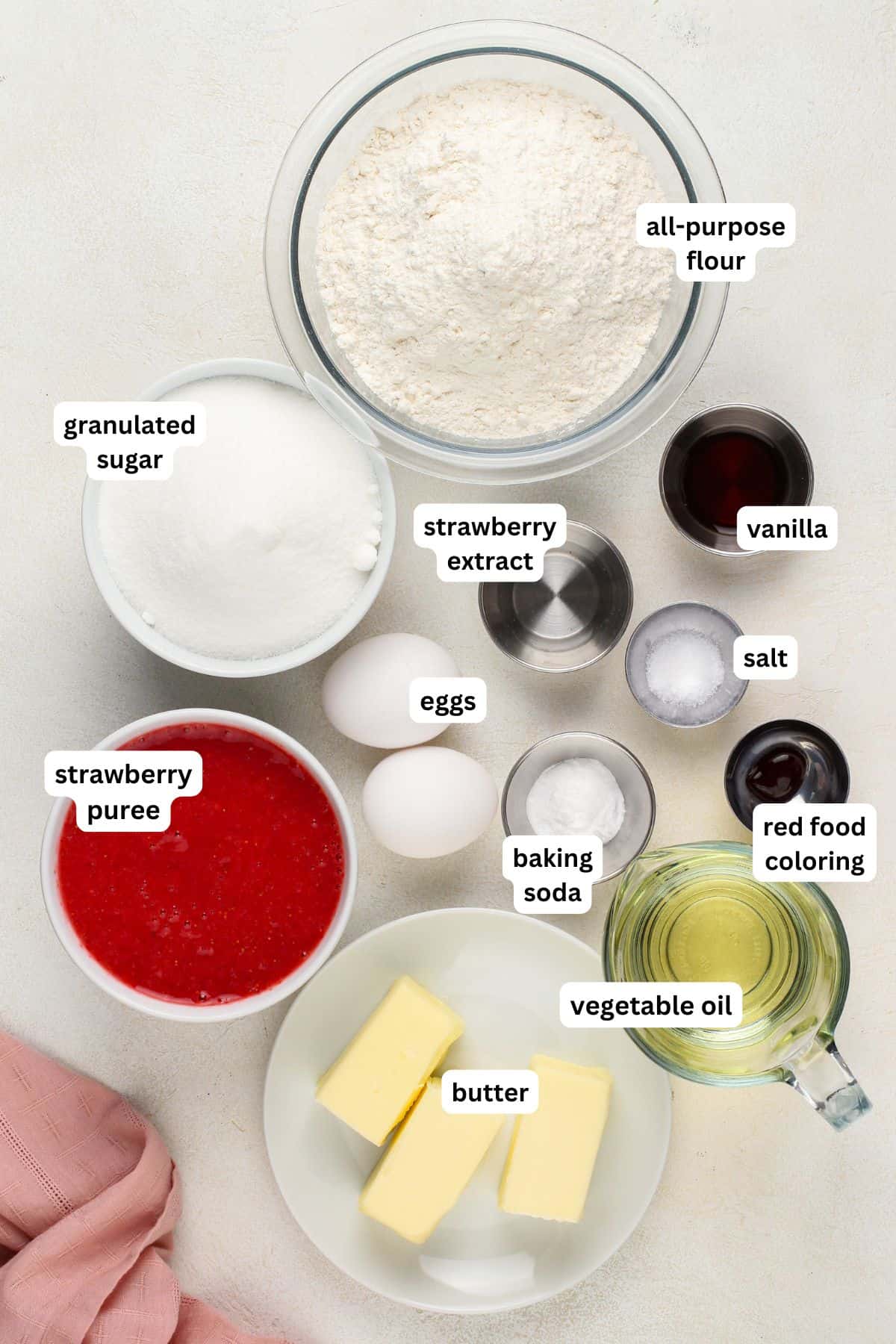 Ingredients for homemade strawberry cake recipe in order from top to bottom: all purpose flour, granulated sugar, strawberry extract, vanilla, salt, eggs, strawberry puree, baking soda, red food coloring, vegetable oil, butter.